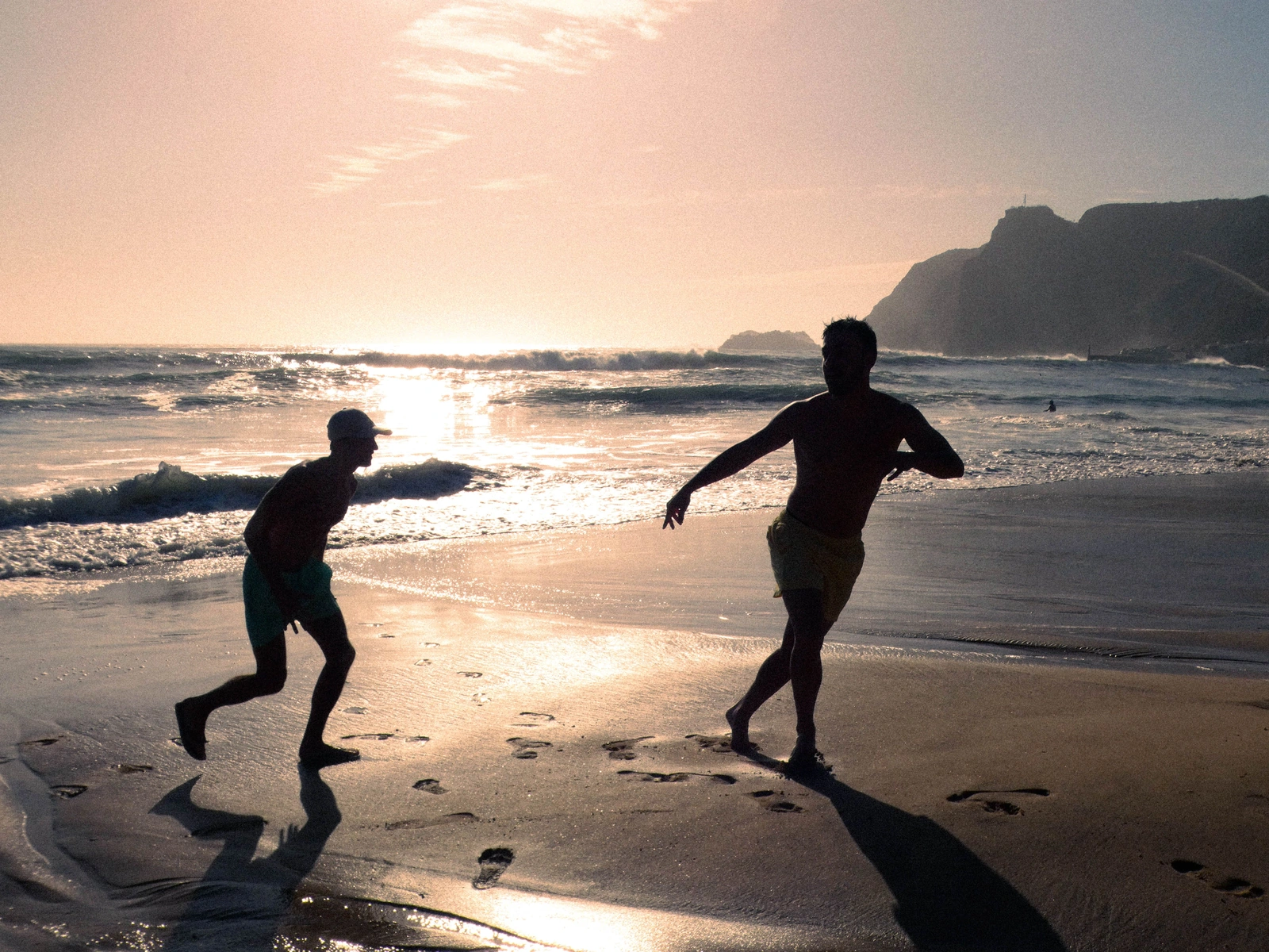 Two people running along the beach in warm sunset light